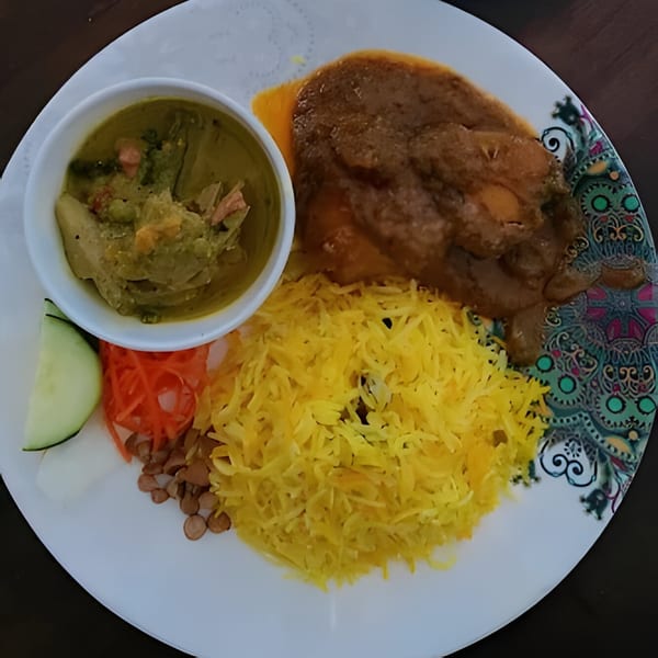 Rakhi's Kitchen fast-food plate with yellow rice, chicken curry, green vegetable curry, and sides.