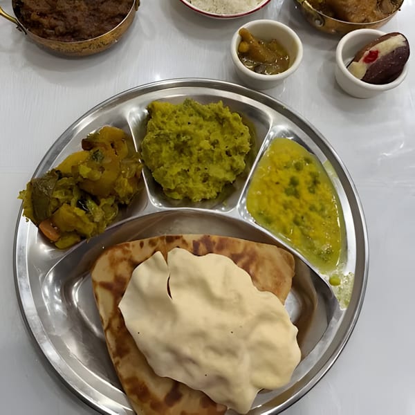 A Rakhi's Kitchen fast-food thali with various Indian dishes, including flatbread, vegetables, and sauces.