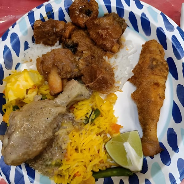 A fast-food meal with rice, chicken, fried fish, and a lime wedge on a blue and white plate.